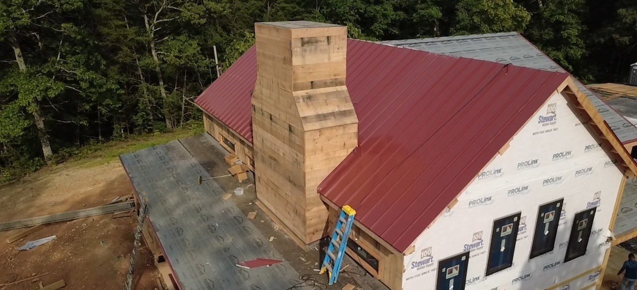 Drone view of a red standing seam metal roof on a timber frame home, Middle Tennessee